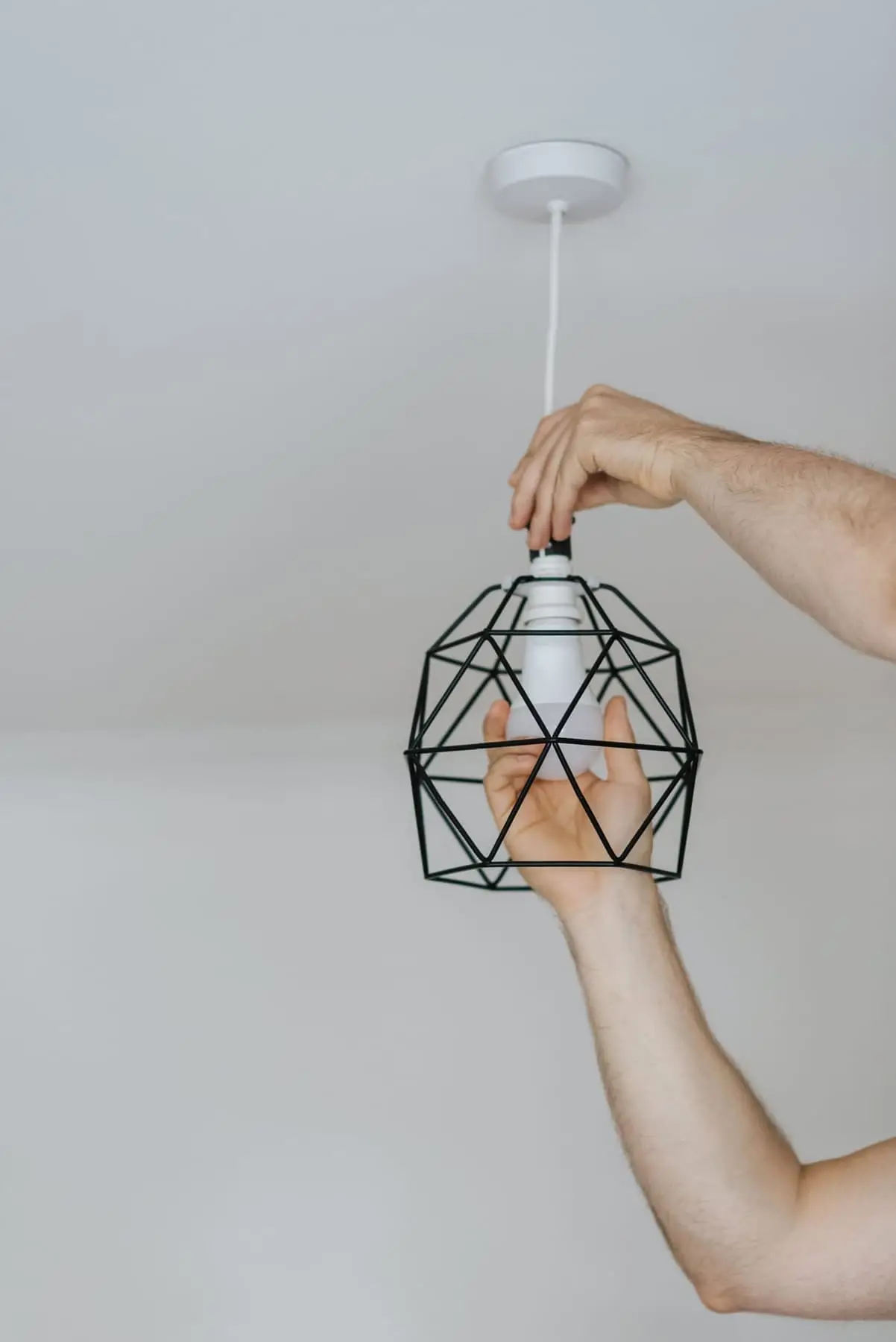 Hænder monterer en lampe i loftet
