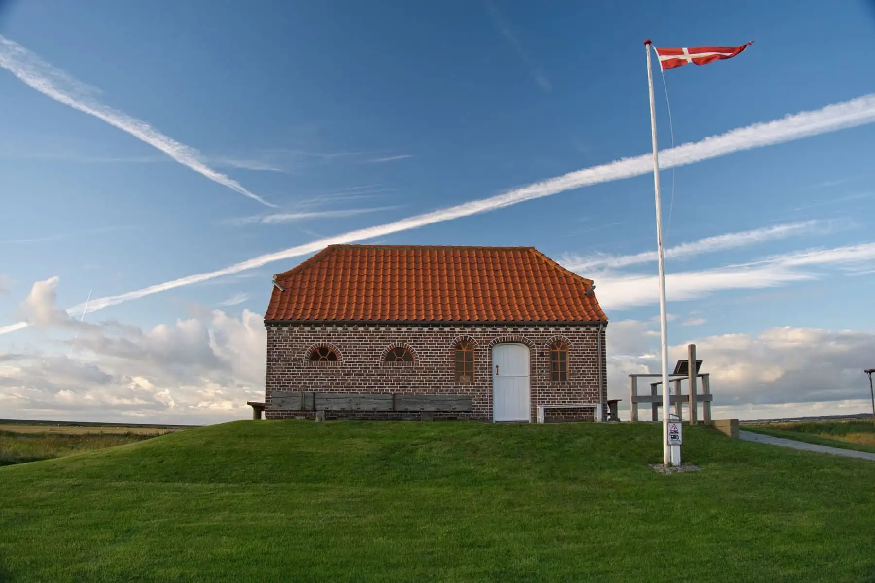 Murstenshus med rødt tegltag og Dannebrog på flagstangen